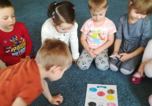 Dzieci na dywanie segregują jajka wg koloru.